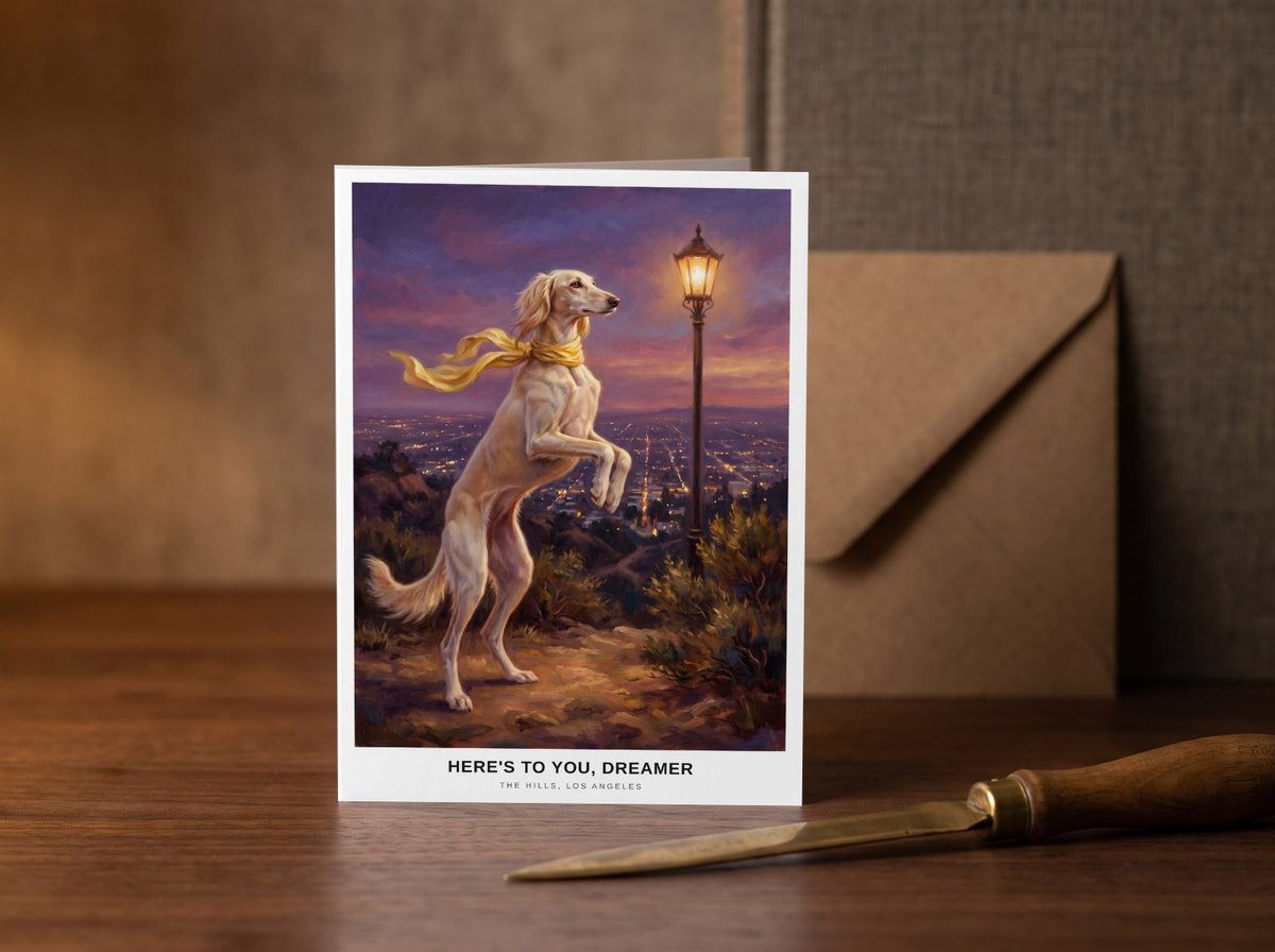 A card standing upright — on a walnut desk with one envelope leaning behind it