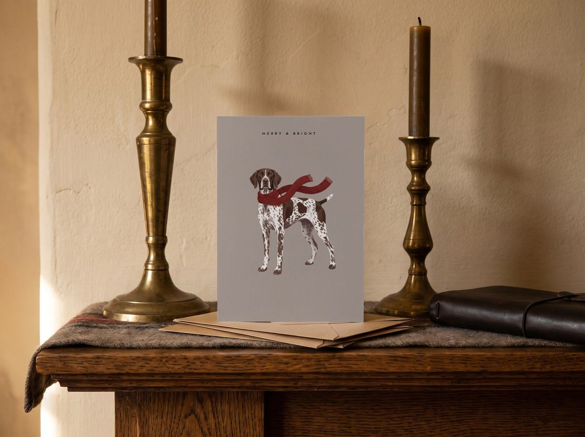 A card standing upright — on a mantel between brass candlesticks